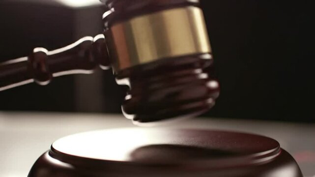 A wooden judge's or auctioneer's gavel striking a sound block, decisive moment.