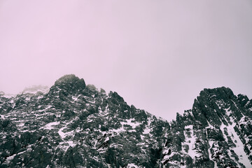 Snow-covered mountain peaks in the Alps under cloudy sky during winter season