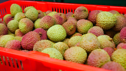 Close-up of many ripe lychees in a red basket