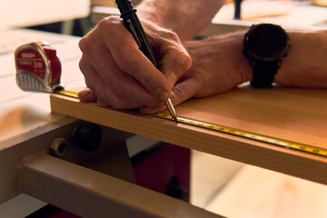 Expert carpenter measures wood with precision tool in Alpine workshop during daylight hours