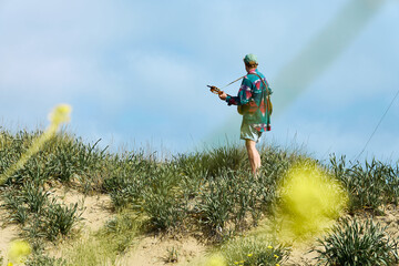 Person playing guitar on alpine hillside surrounded by wildflowers under bright blue sky