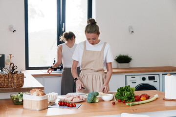 Middle age woman preparing healthy food in bright kitchen with fresh vegetables promoting active wellbeing and wellness lifestyle for longevity and fitness.