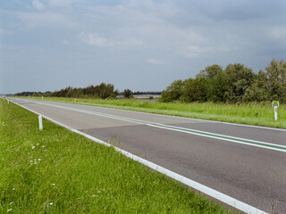 Fototapeta premium A saturated photo of road in the countryside near the Netherlands inner waters in the sunny day, shoot on color negative film 