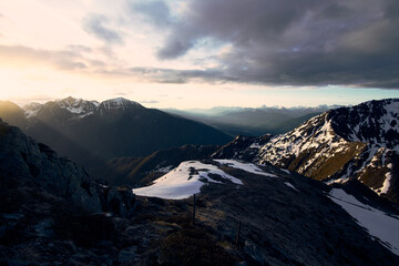 Majestic view of the snowy Alps at sunset, revealing rugged peaks and valleys under a dramatic sky