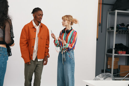 Young adult woman socializing with colleague in casual workplace, showcasing Business, Friends, Coworkers, and Gen Z collaboration in a modern work environment.