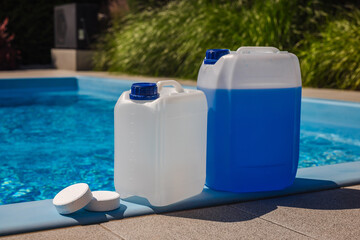 White and blue chemical canisters with chlorine tablets placed on the edge of a clean swimming...