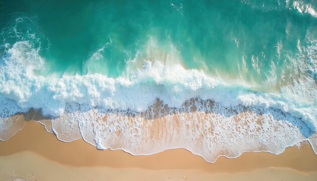 Aerial view of turquoise ocean waves crashing on beach shoreline. White foamy sea water meets golden sand. Tropical summer day, nature background, travel, vacation, holiday atmosphere.