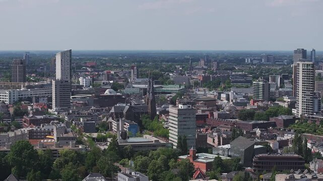 Aerial panning view of Eindhoven, Netherlands, showing Philips Stadium, St. Catherine's Church, urban skyline, green spaces, and flat terrain in daylight.