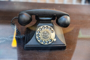 London, UK, 12 May 2025,  A vintage black rotary dial telephone on a wooden surface on a flea market