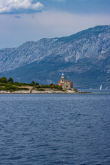 Fototapeta premium Leuchtturm auf der Insel Hvar vor der felsigen Landschaft des kroatischen Festlands