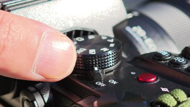 Photographer's finger rotating the mode dial of a modern mirrorless camera