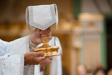 Catholic Priest Holding the Holy Eucharist Chalice During Religious Ceremony in Church Gold Interior