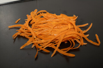 Carrot waste on black table and vegetable peeler.View of pile of various organic waste after...