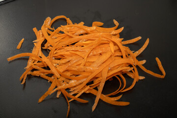 Carrot waste on black table and vegetable peeler.View of pile of various organic waste after...