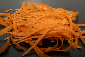 Carrot waste on black table and vegetable peeler.View of pile of various organic waste after...