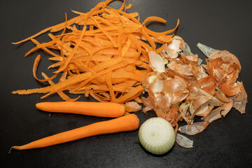 Onion peel and carrot waste on black table and vegetable peeling knife.View of pile of various...
