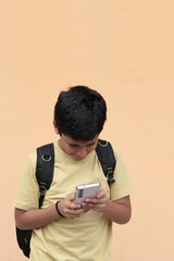 A 10-year-old Latino boy uses his cell phone to play video games, make video calls, send messages,...