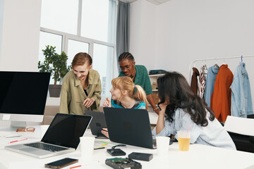 Young adult women colleagues working together and socializing in a modern workplace, showcasing Gen Z coworkers collaborating in a friendly business environment.