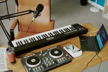 Electronic music production setup featuring digital piano keyboard, DJ controller, audio mixer,...