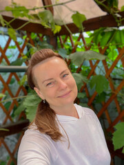 portrait of a mature woman in a summer gazebo with a vine background