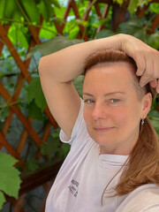portrait of a mature woman in a summer gazebo with a vine background