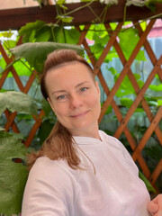 portrait of a mature woman in a summer gazebo with a vine background