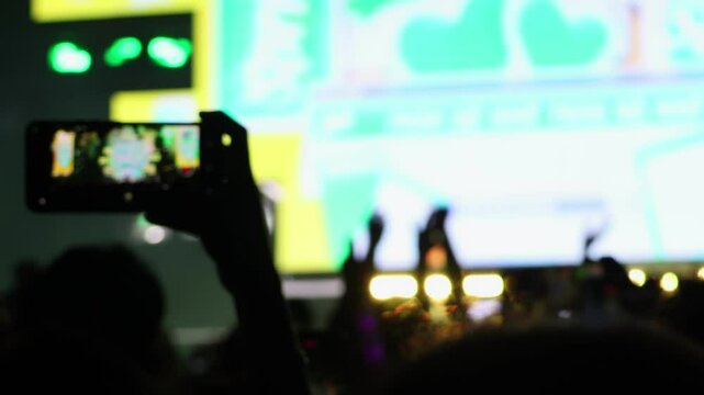 Bokeh view of people dancing on the dance floor during a concert at a festival. Blurred background footage. Concept of crowd enjoying rock and roll, live dj set, hip hop rap party, night club event.