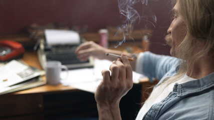Moody close-up of a man smoking at his desk, atmospheric lighting highlighting addiction and...