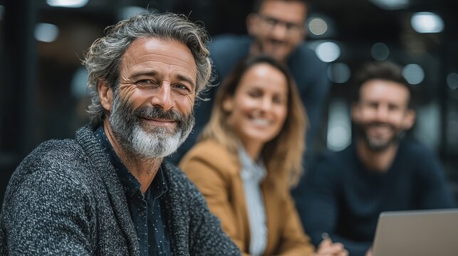 Smiling senior businessman with colleagues attending a meeting in an office during the day - Powered by Adobe