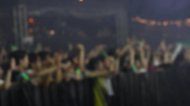 Bokeh view of people dancing on the dance floor during a concert at a festival. Blurred background footage. Concept of crowd enjoying rock and roll, live dj set, hip hop rap party, night club event.