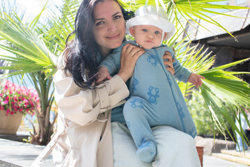 woman with 6 month old baby sitting near palm tree in summer