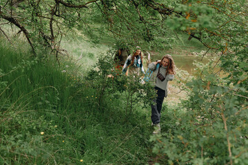 Active middle age woman hiking through lush green forest trail with another older woman, enjoying...
