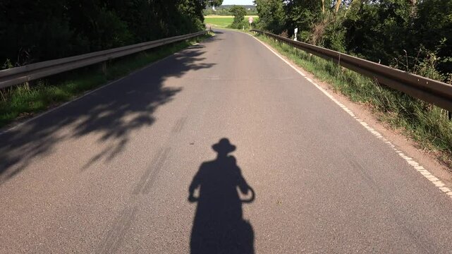 Schatten eines Radfahrers auf dem Asphalt einer Landstrasse