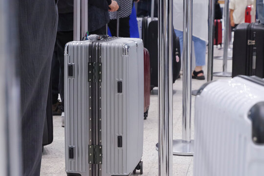 飛行機の荷物預かりに並ぶ人とスーツケース