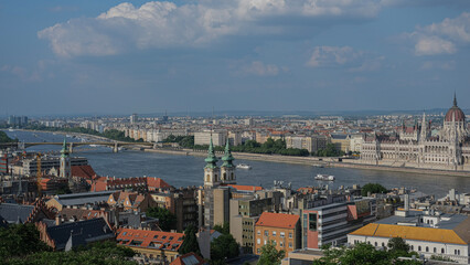 Wide-angle view of the Hungarian Parliament Building and Danube River with boats and surrounding architecture in Budapest.