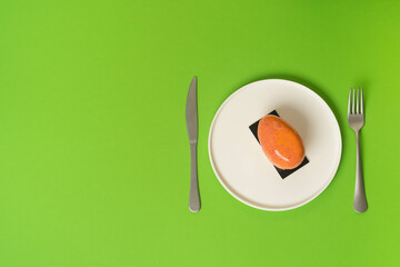Single salmon slice on white plate, green background.
