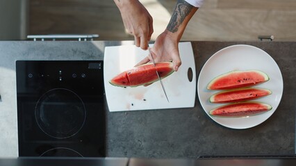 Chef preparing fresh watermelon slices on a white cutting board in a modern kitchen
