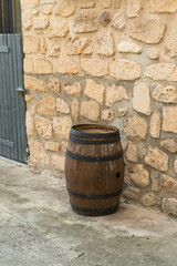 Wooden barrel against rustic stone wall.
