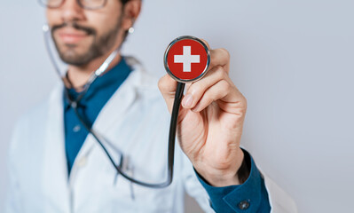 Doctor holding stethoscope with Switzerland flag. Switzerland health and care concept, Switzerland flag on stethoscope