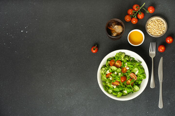 Chicken and salad with pine nuts on dark background.