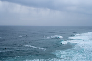 Multiple jet skis and surfers ride powerful waves in open ocean during big wave surfing event....