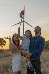 Family with son walking on field on wind farm. Happy Family and son playing at the Wind turbines...