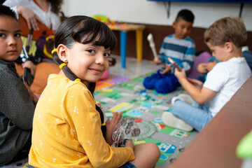Kindergarten children smile while playing musical instruments with their teacher in a colorful...