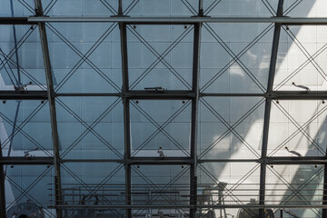 Fototapeta premium The architectural detail shows a grid of steel beams filled with perforated panels, with the small silhouette of a person on a walkway indicating the immense scale. 