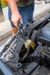 Man filling water into windscreen water tank in car engine room, for window wiper 