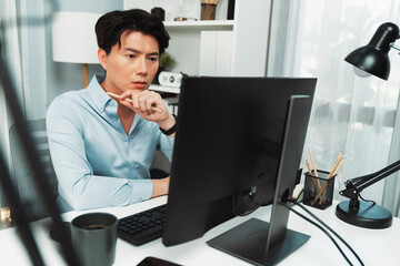 Serious smart businessman working on computer to check email with business project report,...