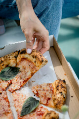 A woman takes a slice of Margherita pizza.