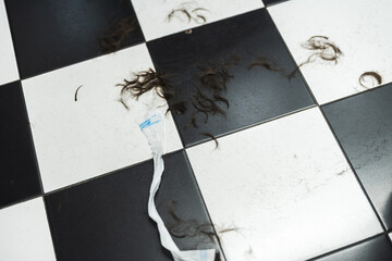 Hair and debris scattered on a stylish black and white tiled floor