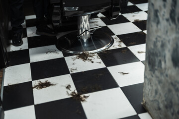 Hair strands scattered on the floor of a trendy barbershop in the city