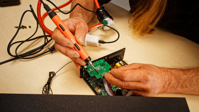 A volunteer specialist hand soldering a repair of electronic audio equipment at the Motueka Repair Cafe, New Zealand.